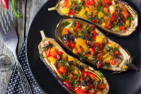 Berenjenas rellenas de verduras, con pimientos rojos y amarillos, hierbas frescas y un toque de aceitunas negras.