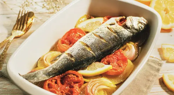 Lubina al horno con patatas, tomates y limón, lista para disfrutar.