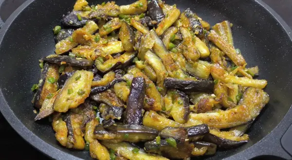 Berenjenas al ajillo salteadas en sartén, con trozos dorados y tiernos, salpicadas de ajo y perejil.
