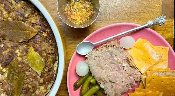 Pate de campaña casero, servido con pepinillos, cebollitas y galletas saladas. Un festín rústico.