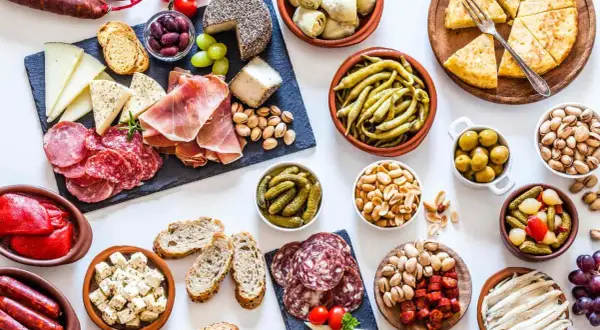 Gran variedad de aperitivos baratos para mucha gente: embutidos, quesos, aceitunas, frutos secos, pimientos, boquerones y tortilla.