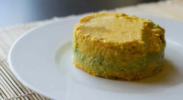 Pastel de calabacín, jamón y queso, con capas verdes y amarillas, servido en plato blanco.
