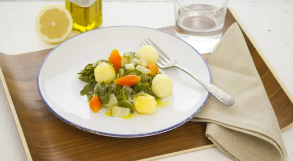 Plato de acelgas con patatas, zanahoria y cebolla, acompañado de limón, aceite de oliva y agua.