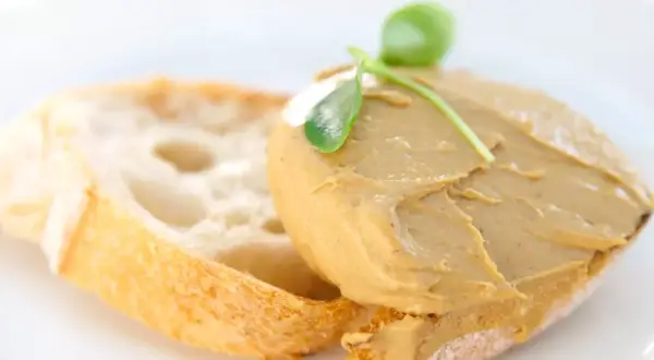 Tostada con paté de mejillones y una hoja verde como decoración.
