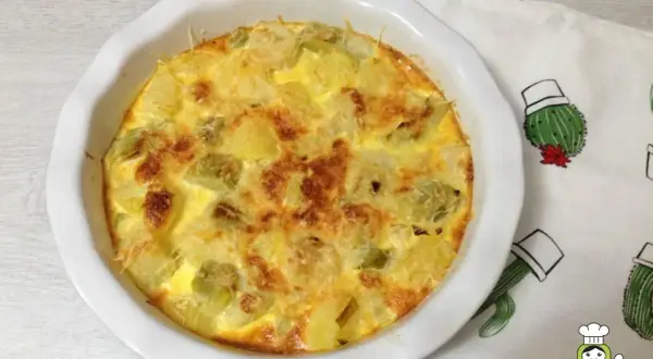 Tortilla dorada con trozos de puerros al horno y queso gratinado, lista para disfrutar.