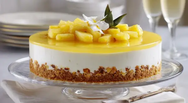 Deliciosa tarta de piña con trozos de fruta fresca y una capa de gelatina brillante, sobre una base crujiente.