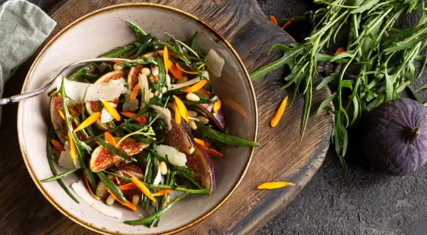 Ensalada gourmet con higos frescos, rúcula, piñones y láminas de queso. Perfecta para tus recetas con higos frescos.