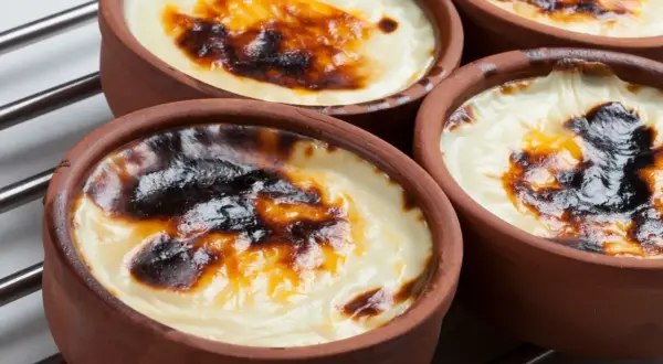 Cuatro cazuelas de barro con tarta de arroz horneada, con una capa superior dorada y caramelizada.