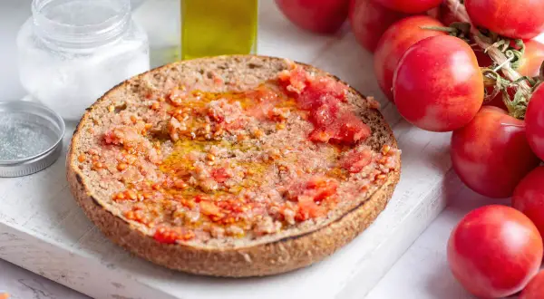 Rebanada de pan tostado con tomate rallado y aceite de oliva, lista para disfrutar de un delicioso pa amb tomàquet.