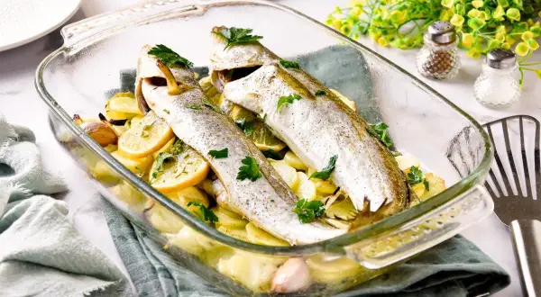 Pescadilla al horno con patatas, limón y ajo, recién salida del horno.