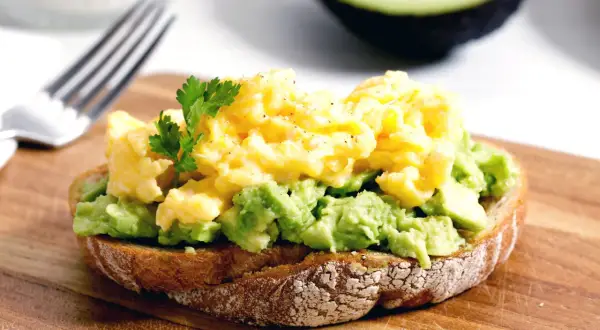 Tostada con aguacate machacado y huevos revueltos, una de las mejores recetas con aguacate.