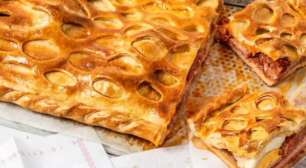 Un delicioso hornazo de Salamanca, con su masa dorada y relleno de carne y huevo duro, listo para ser disfrutado.