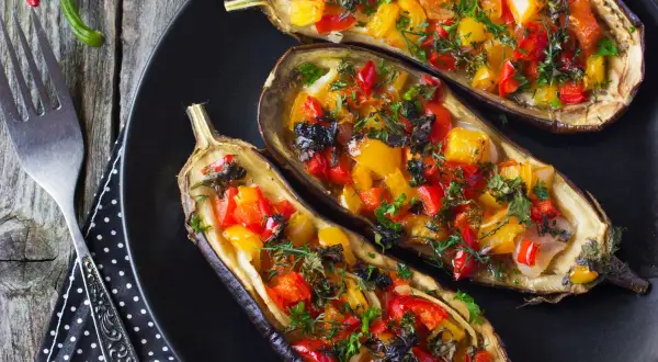 Berenjenas rellenas de verduras, con pimientos rojos y amarillos, hierbas frescas y un toque de aceitunas negras.
