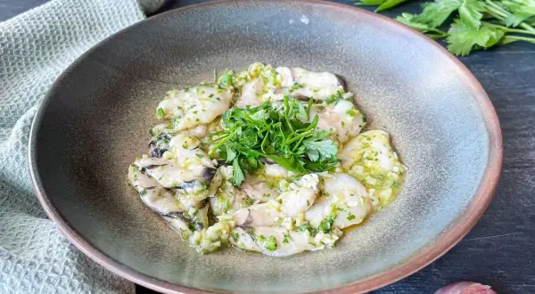 Deliciosas cocochas de merluza en salsa de ajo y perejil, servidas en un cuenco rústico.