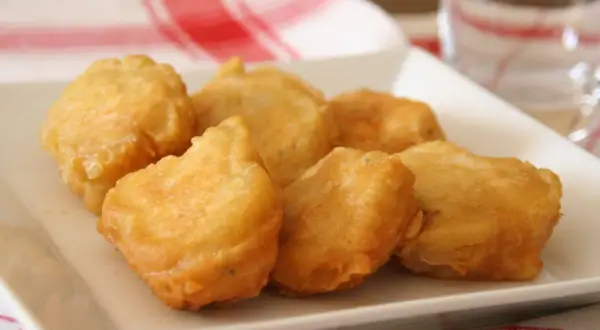 Bocados dorados y crujientes, ¿qué es la pavía pescado? Deliciosos trozos de pescado rebozado en una bandeja blanca.