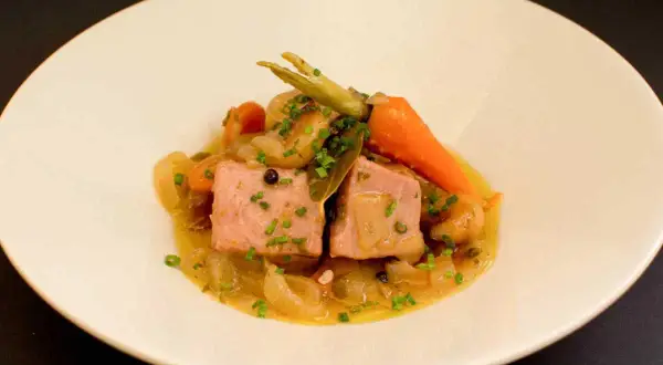 Dos trozos de atún en escabeche con zanahorias y cebolla, servidos en un plato blanco.