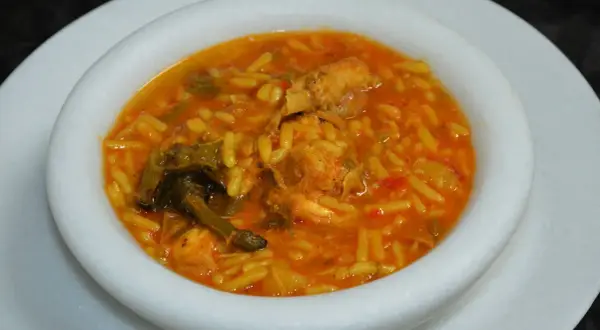 Un plato de gurullos con conejo, un guiso tradicional con pasta corta y trozos de carne de conejo en una salsa rojiza.