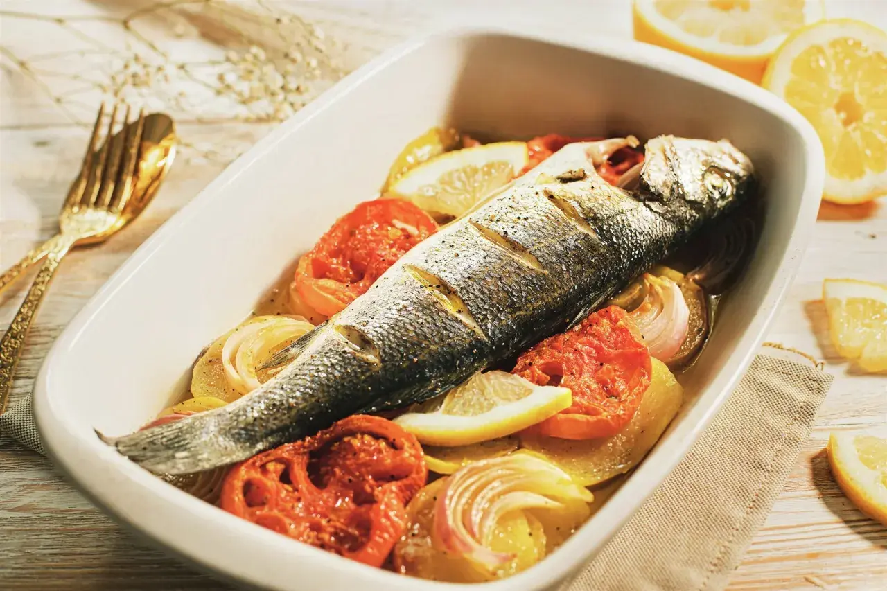 Lubina al horno con patatas, tomates y limón, lista para disfrutar.
