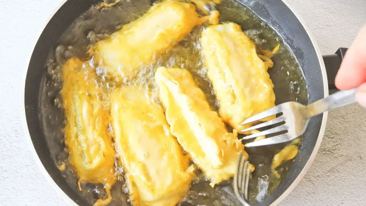 Soldaditos de pavia dorándose en aceite caliente. Un tenedor los voltea para una fritura perfecta.