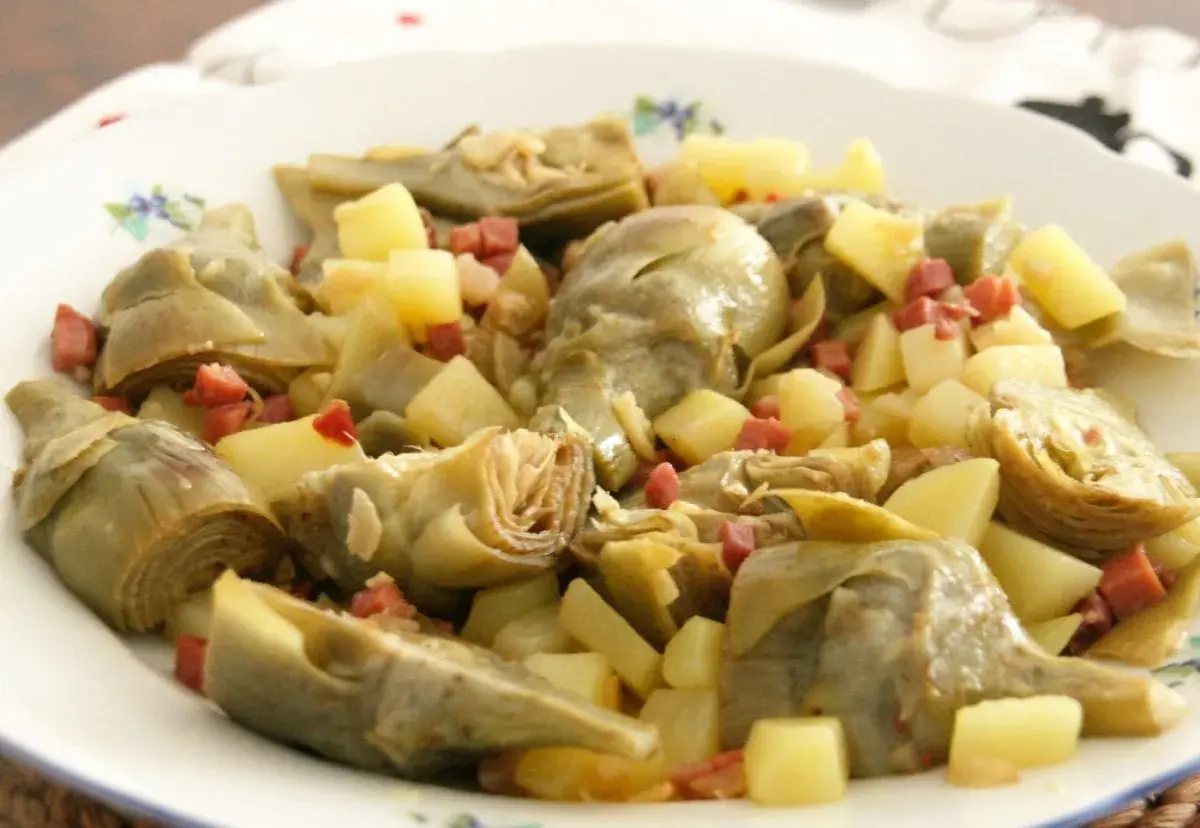 Plato de alcachofas tiernas y trocitos de patata, salpicado con dados de jamón serrano. Un bocado delicioso.