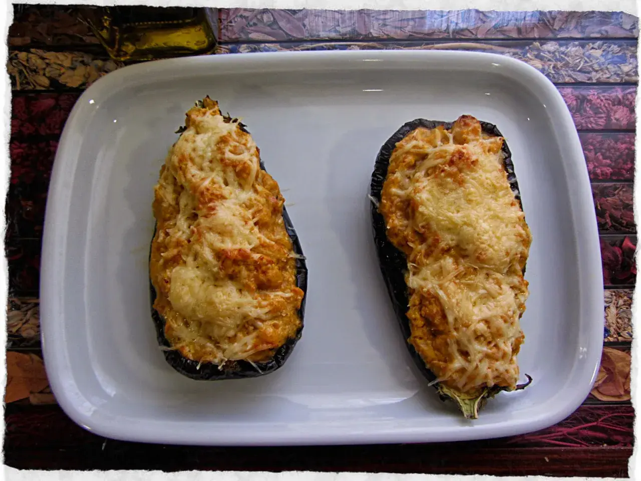 Dos berenjenas rellenas de gambas, gratinadas con queso, listas para disfrutar.