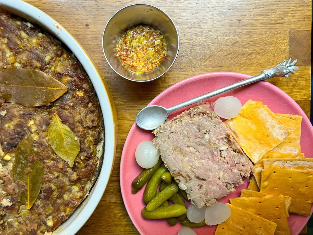 Pate de campaña casero, servido con pepinillos, cebollitas y galletas saladas. Un festín rústico.