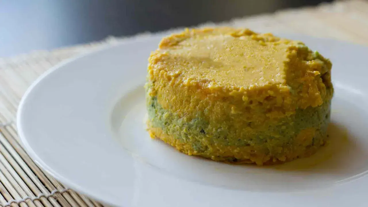 Pastel de calabacín, jamón y queso, con capas verdes y amarillas, servido en plato blanco.