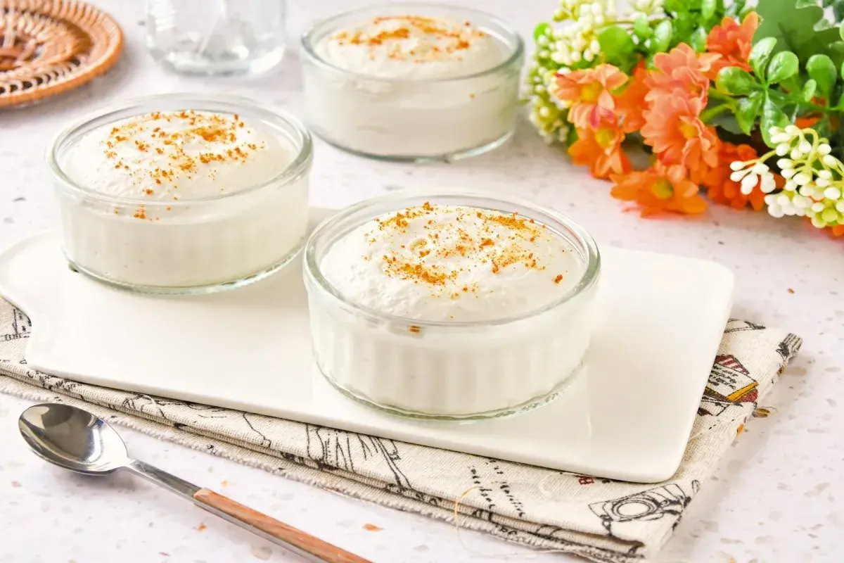 Delicioso mousse de yogur en vasitos de cristal, espolvoreado con canela. Un postre ligero y refrescante.