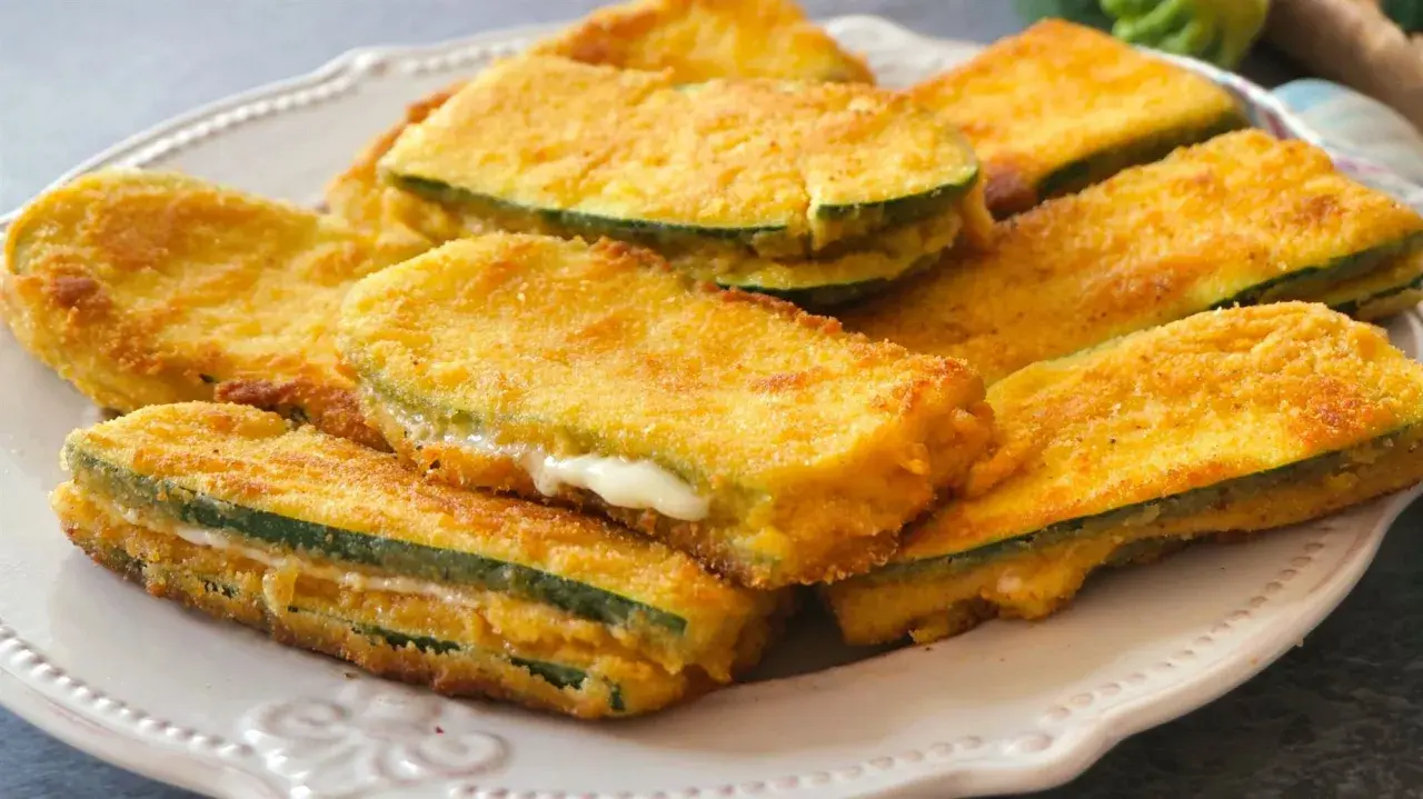 San jacobos de calabacín dorados y crujientes, rellenos de queso fundido, servidos en un plato blanco.