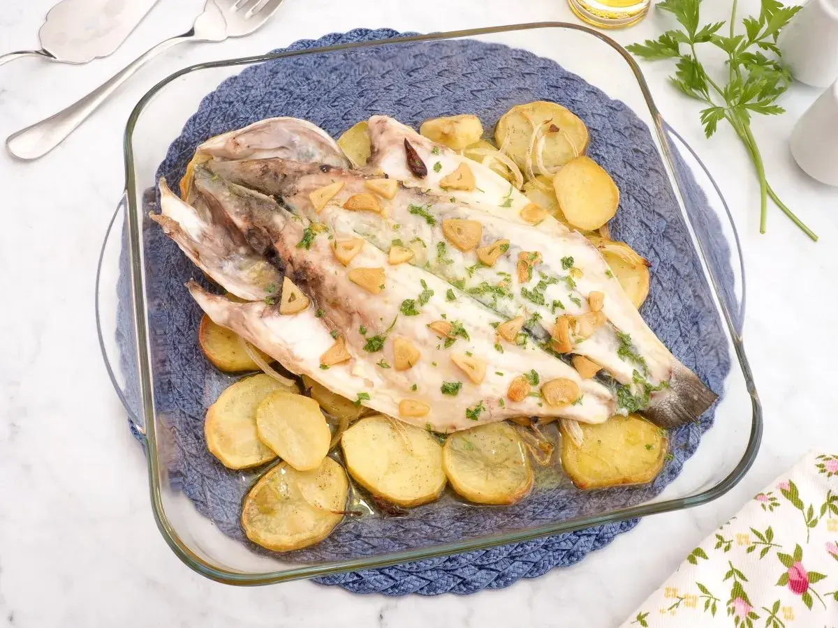 Lubina al horno con patatas y ajo, recién salida del horno, lista para servir.