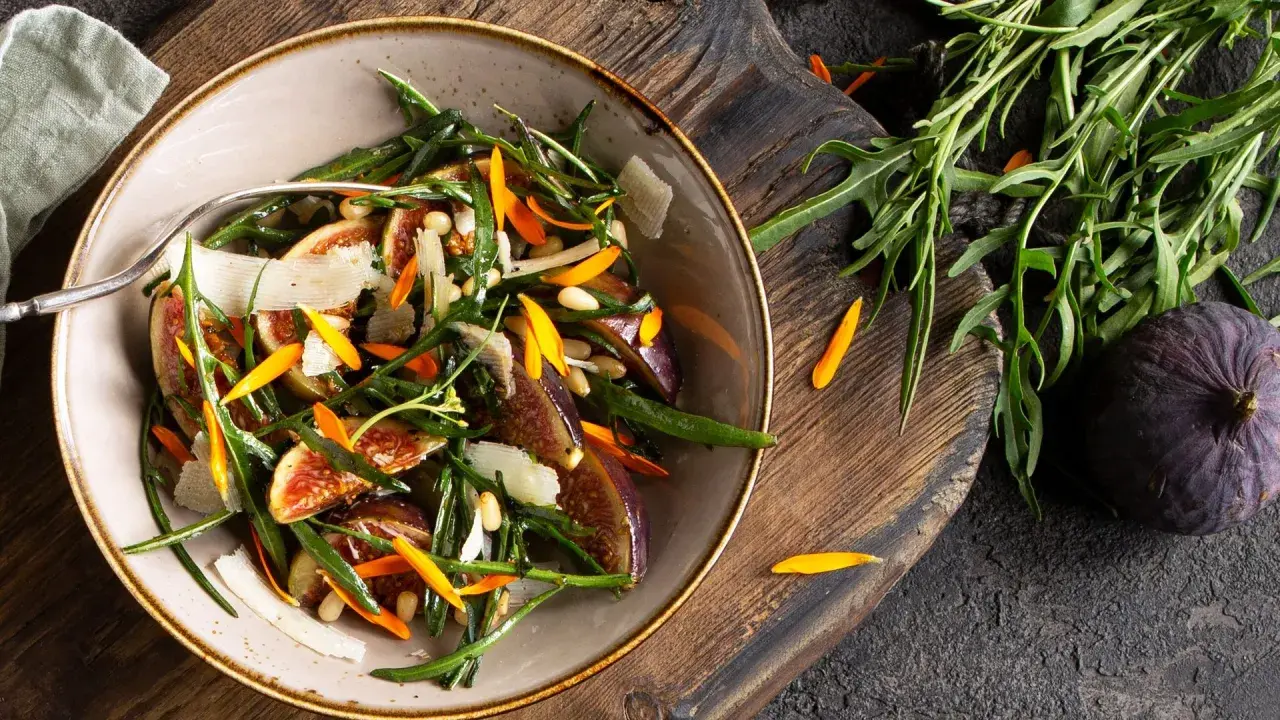 Ensalada gourmet con higos frescos, rúcula, piñones y láminas de queso. Perfecta para tus recetas con higos frescos.