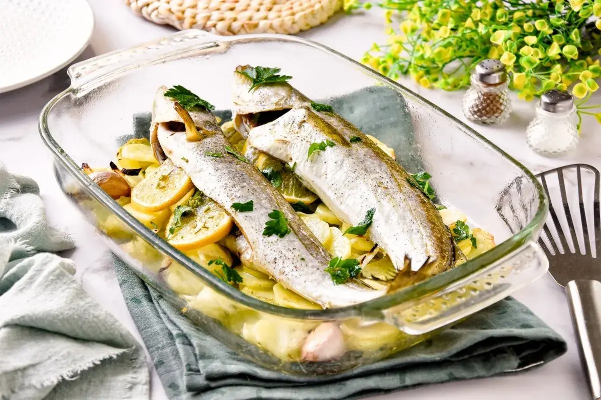 Pescadilla al horno con patatas, limón y ajo, recién salida del horno.