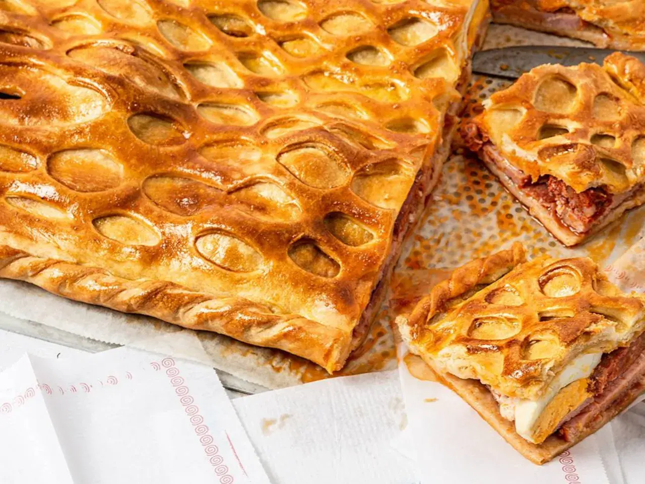 Un delicioso hornazo de Salamanca, con su masa dorada y relleno de carne y huevo duro, listo para ser disfrutado.