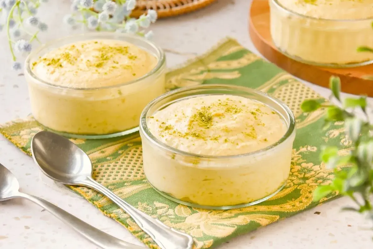 Delicioso mousse de mango en copas de cristal, espolvoreado con ralladura verde.