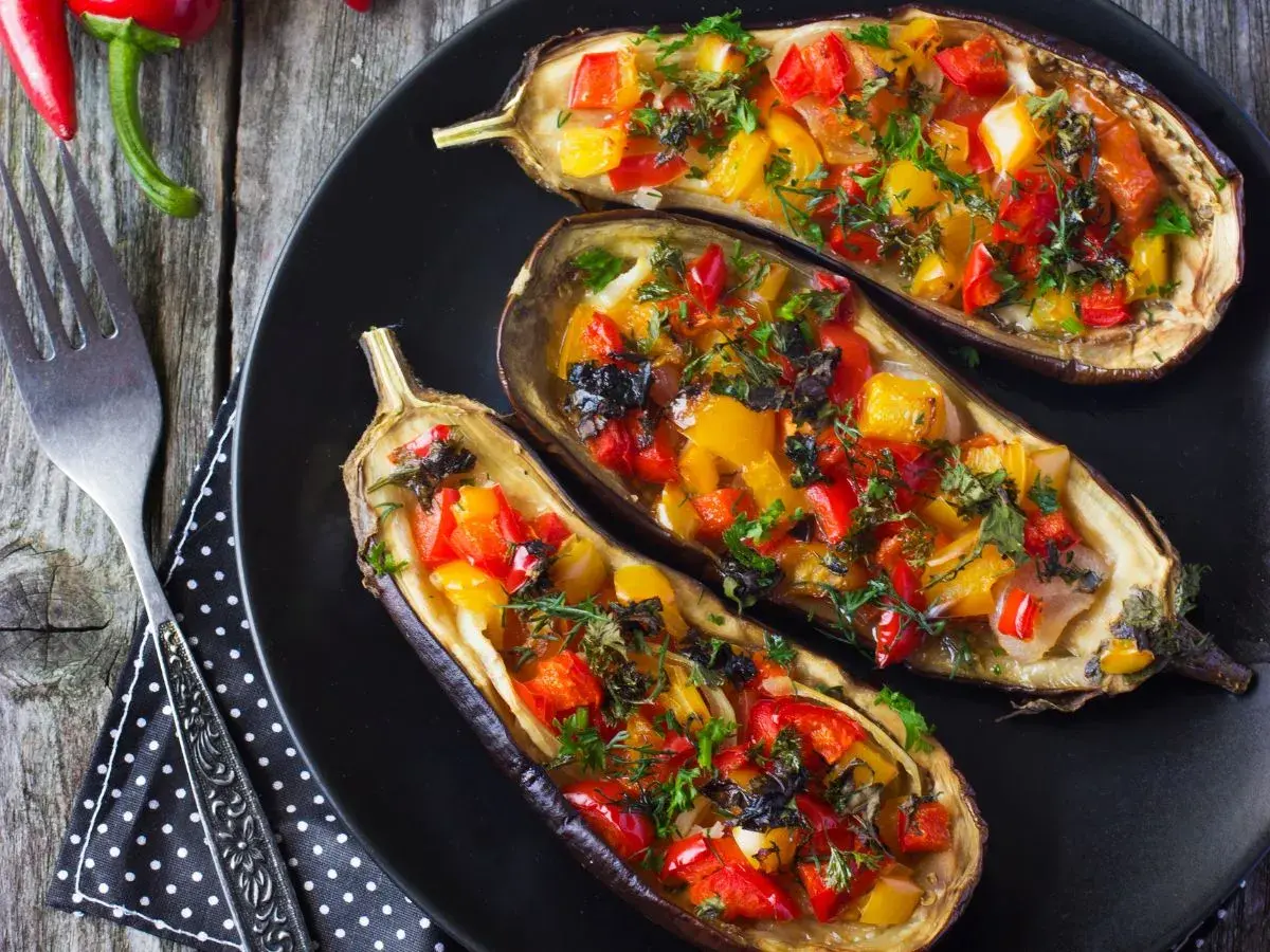 Berenjenas rellenas de verduras, con pimientos rojos y amarillos, hierbas frescas y un toque de aceitunas negras.