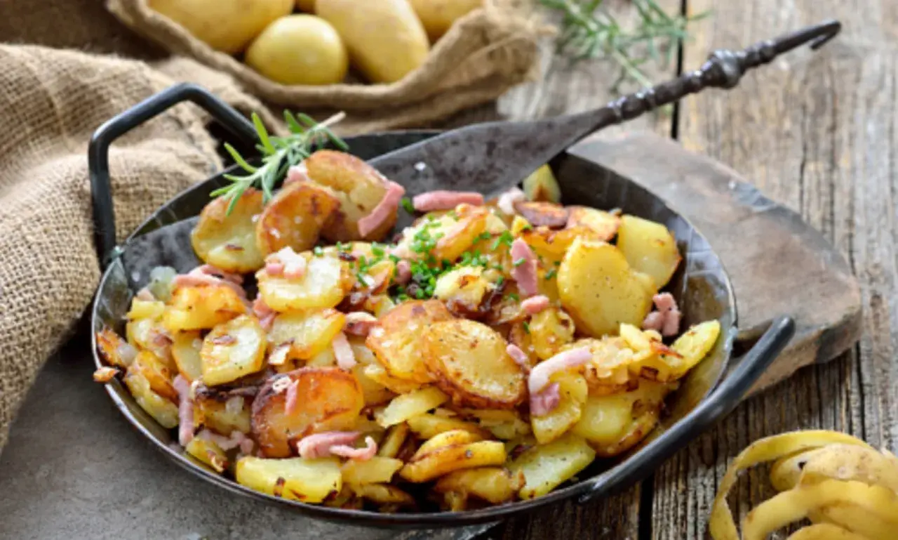 Patatas con bacon y queso, doradas y crujientes, servidas en una sartén de hierro fundido. Un plato perfecto para compartir.