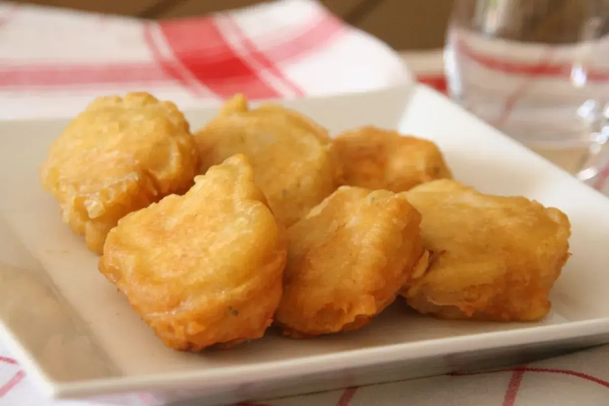 Bocados dorados y crujientes, ¿qué es la pavía pescado? Deliciosos trozos de pescado rebozado en una bandeja blanca.