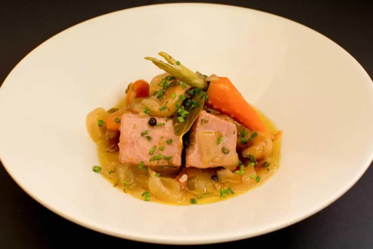 Dos trozos de atún en escabeche con zanahorias y cebolla, servidos en un plato blanco.