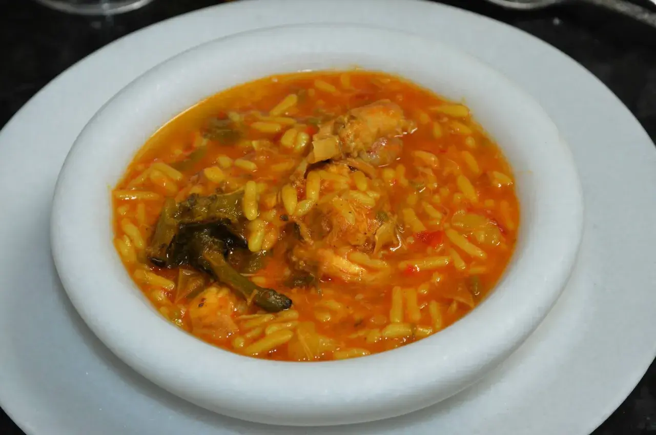 Un plato de gurullos con conejo, un guiso tradicional con pasta corta y trozos de carne de conejo en una salsa rojiza.
