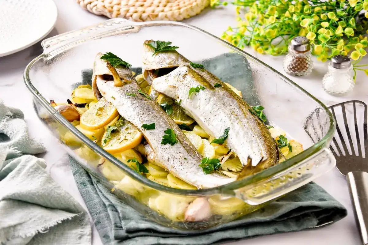 Pescadilla al horno con patatas, lim&oacute;n y ajo, reci&eacute;n salida del horno.