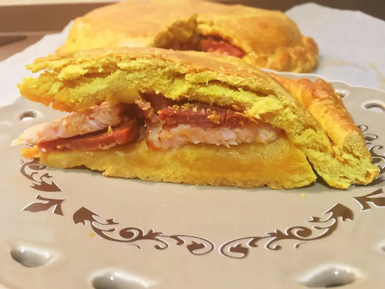 Un trozo de hornazo de Salamanca, relleno de carne y chorizo, sobre un plato decorado.