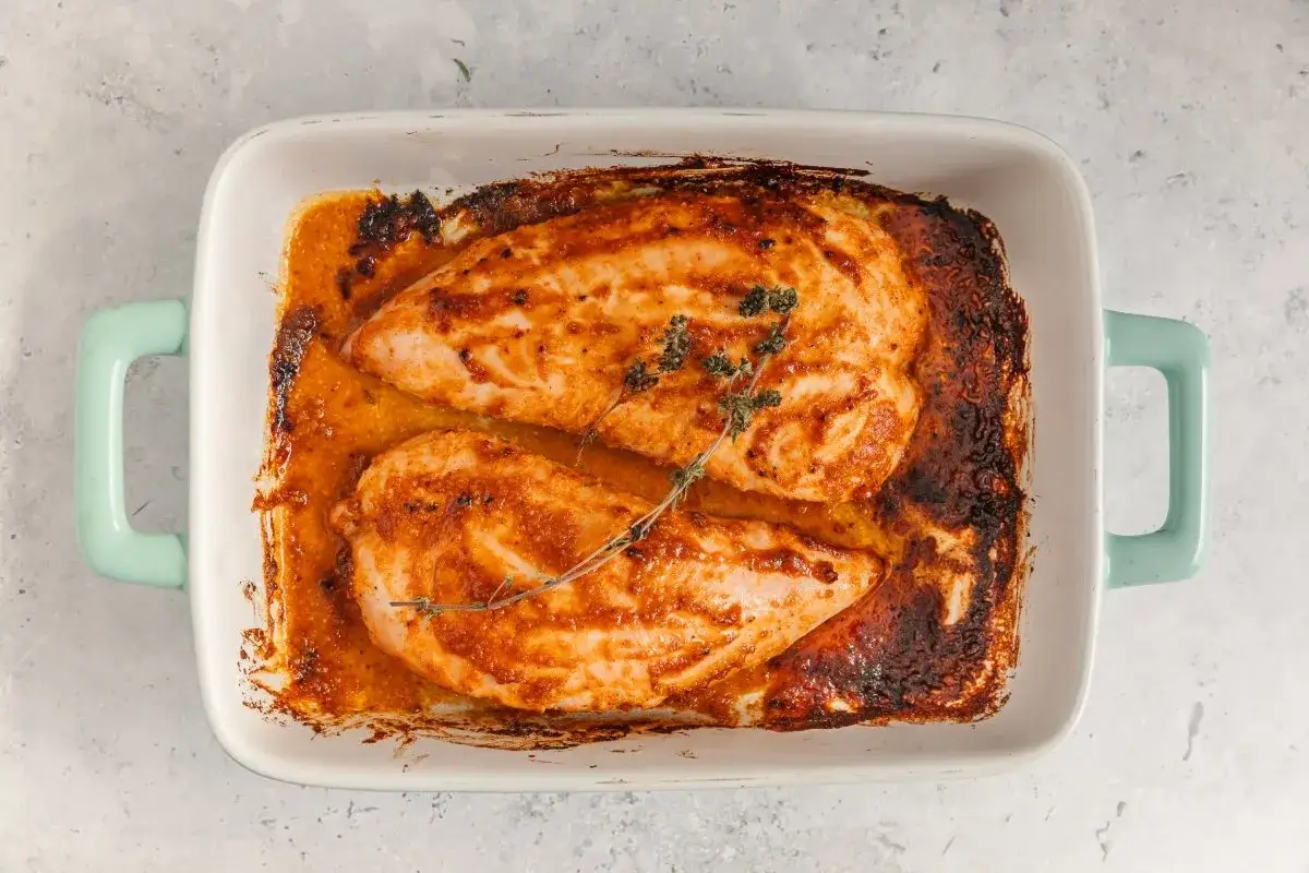 Dos jugosos solomillos de pavo al horno, dorados y con hierbas arom&aacute;ticas, reposan en una bandeja blanca con asas turquesa.