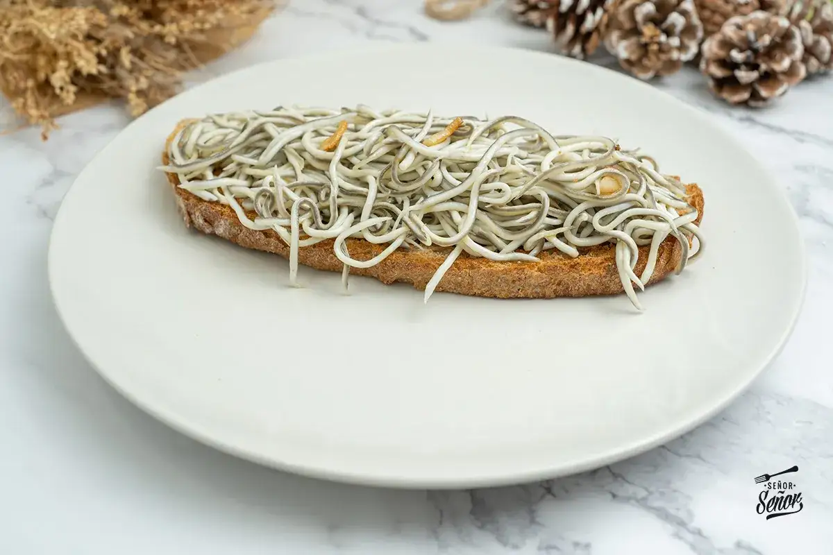 Una deliciosa tosta de gulas con ajo y perejil sobre pan r&uacute;stico, lista para disfrutar.