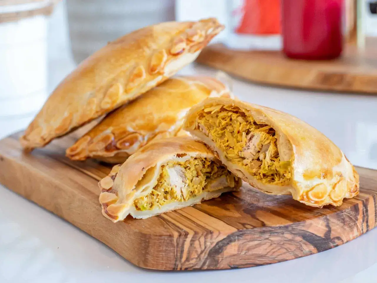 Empanadas de pollo doradas y crujientes, una rellena abierta revela su sabroso interior.