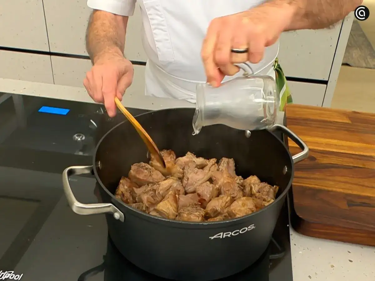 Un chef a&ntilde;ade l&iacute;quido a un choto al ajillo en una olla.