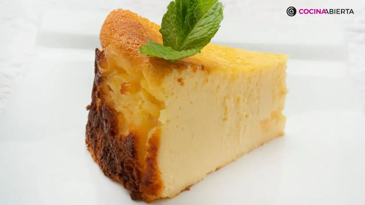 Rebanada de tarta de queso cremosa, con bordes dorados y decorada con una hoja de menta fresca.
