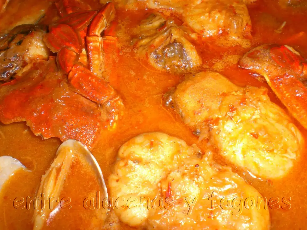 Caldereta de pescado con trozos de marisco y pescado en una salsa naranja.