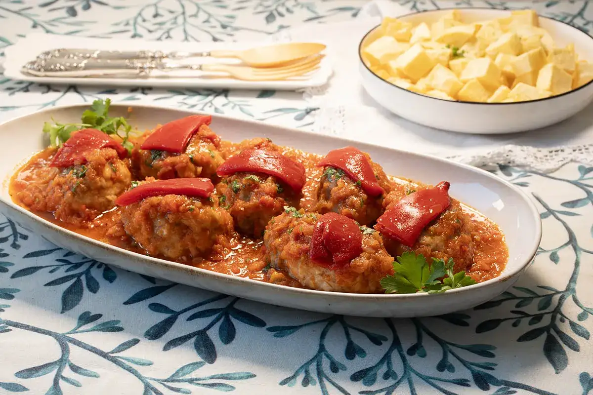Rollo de bonito, receta de la abuela, servido en salsa de tomate con pimientos rojos y perejil. Acompa&ntilde;ado de patatas fritas.