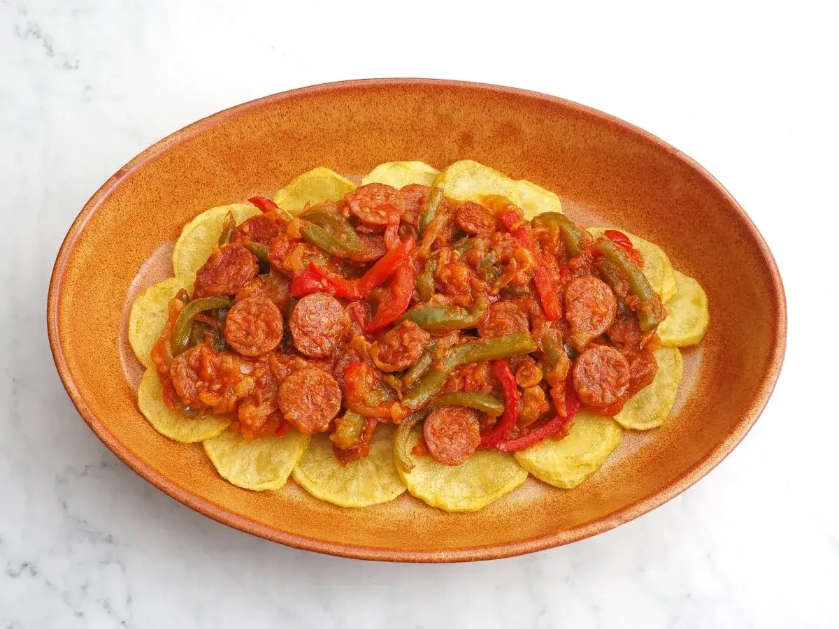 Plato de huevos a la riojana con patatas fritas en rodajas, chorizo, pimientos y tomate.