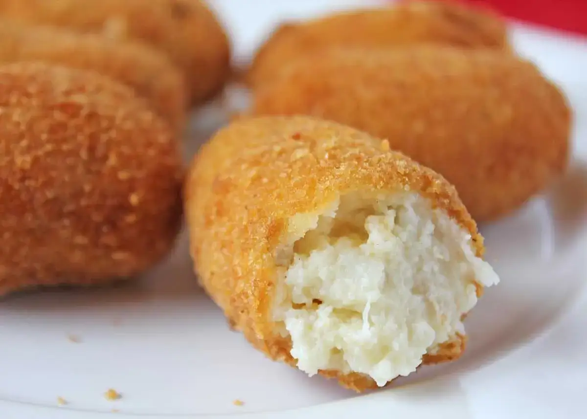 Croquetas de bacalao doradas y crujientes, con un interior cremoso y blanco. Un bocado delicioso.